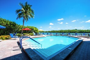 Una piscina al aire libre, sombrillas, tumbonas