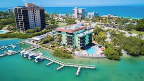 Vista aérea de un resort con un puerto deportivo, una piscina y edificios con balcones con vistas al agua.