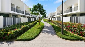 Een modern wooncomplex met een centrale pad, omzoomd door keurig gesnoeide hagen en bloeiende planten.