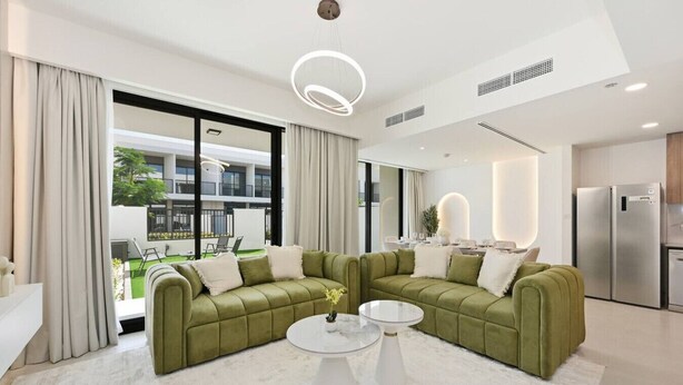 Een moderne woonkamer met een hoekbank, een ronde salontafel en uitzicht op het balkon.