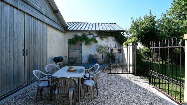 Eine Terrasse mit Tisch und Stühlen, einem Grill und einem Tor mit der Aufschrift 'Les SALINES'.