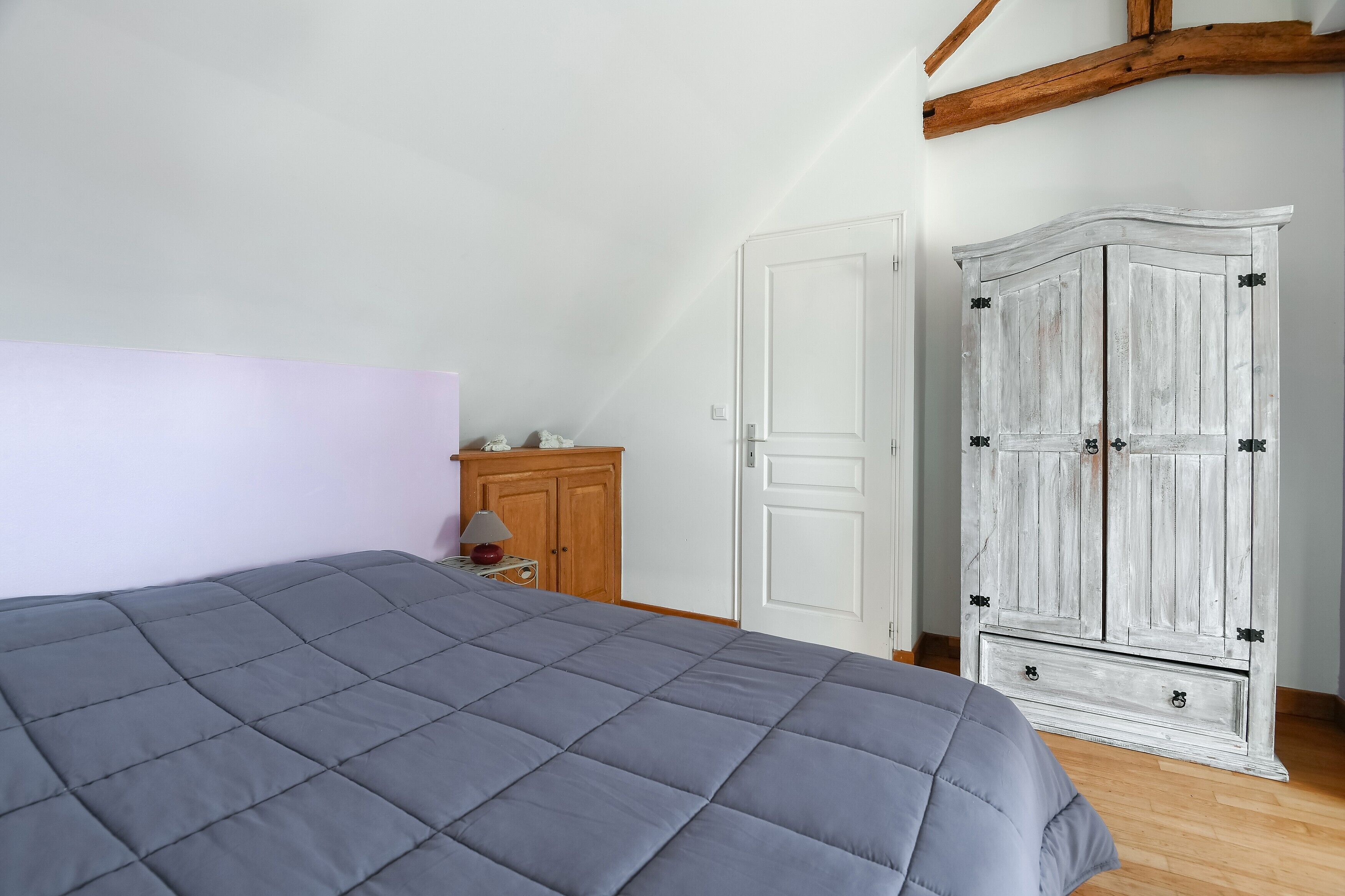 Ein Schlafzimmer mit einem großen Bett, einem Holzschrank und einer weißen Tür.