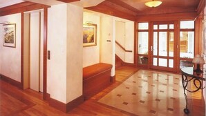 Ein geräumiger Korridor mit Holzboden, einer Treppe und einer großen Glasdoor, die nach draußen führt.