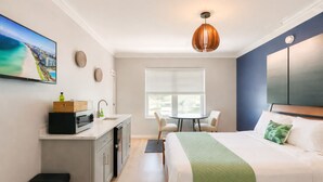 Habitación de hotel con cama, escritorio con lavamanos, una silla y ventana.