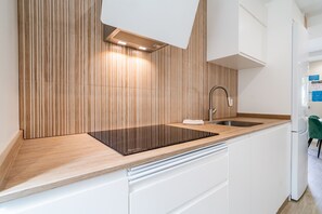 Eine moderne Küche mit Holzrückwand, einem eingebauten Herd und einem Spülbecken.