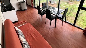 Una habitación moderna con comedor, ventanas amplias y vista a zonas verdes.
