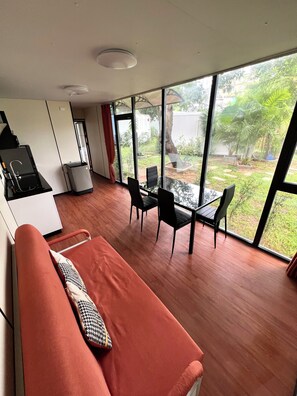 Una habitación moderna con comedor, ventanas amplias y vista a zonas verdes.