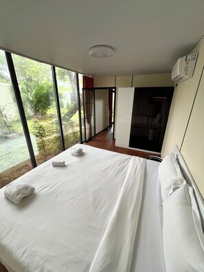 Une chambre d’hôtel avec un grand lit, une armoire et une vue sur un jardin.