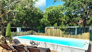 Una piscina con sillas de descanso y una terraza de madera.