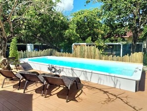 Una piscina con sillas de descanso y una terraza de madera.