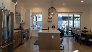 Una cocina moderna con electrodomésticos de acero inoxidable, una isla central y un comedor con vistas al exterior.