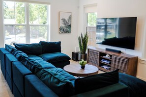 Una sala de estar moderna con un sofá modular, un televisor de pantalla plana, una mesa de centro de madera y una planta en maceta.
