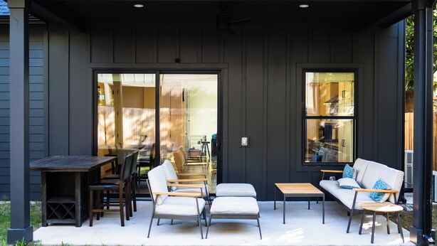 Un patio exterior con mesa de comedor, sillas, sofá y una mesita.