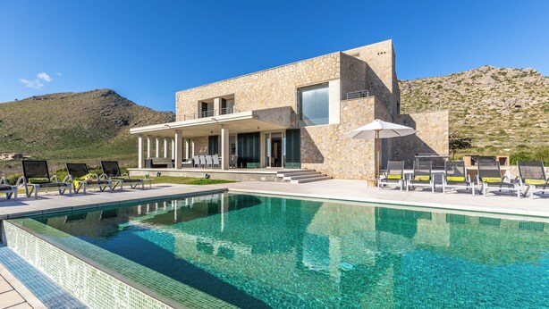 A modern building with a pool, outdoor seating, and a mountainous backdrop. - Unique villa with swimming pool located in the mountains (Las Palmeras)