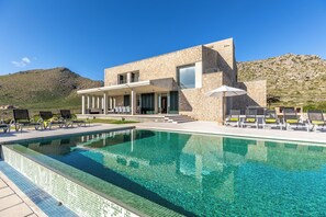 Ein modernes Gebäude mit Pool, Sitzgelegenheiten im Freien und einem Bergpanorama.