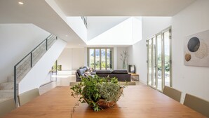 A spacious dining area with a wooden table and a large plant centerpiece. A staircase with a metal railing leads to an upper level. - Unique villa with swimming pool located in the mountains (Las Palmeras)