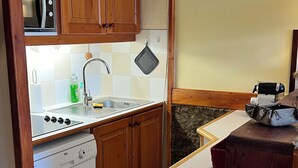 A compact kitchen with wooden cabinets, a built-in microwave, a sink, and a small trash bin. - Les arcs 1800 - T2 827 - 5 pers parking/housekeeping included (Bourg-Saint-Maurice)