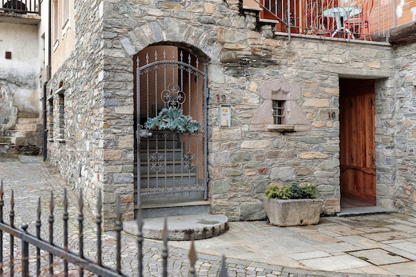 A stone building with a wooden door and a metal gate.