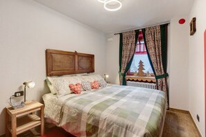 A bedroom with a bed, bedside table, lamp, and curtains.