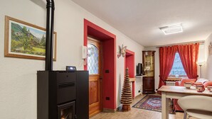 A kitchen with a black stove, a wooden door, and a red wall. - Casa Gardenia Apartment with Mountain View, Private Terrace and Wi-Fi (Rochefort)