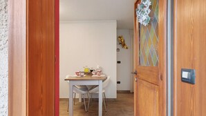 A wooden door with a glass panel, a white table with chairs, and a small decorative item on the wall. - Casa Gardenia Apartment with Mountain View, Private Terrace and Wi-Fi (Rochefort)