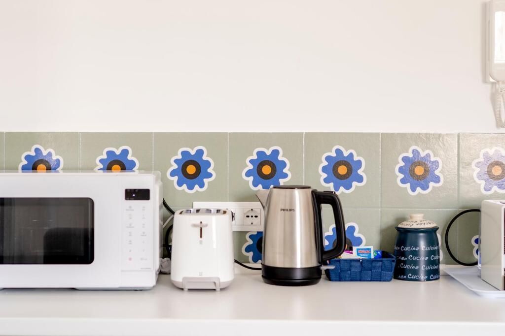Uma cozinha com micro-ondas branco, torradeira, cafeteira e um recipiente azul na bancada.