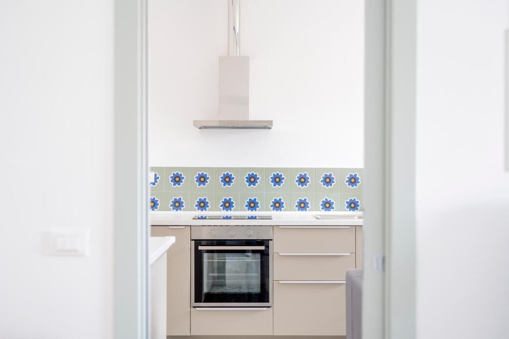 Una cocina con horno empotrado, encimera blanca y salpicadero con azulejos azules y blancos.