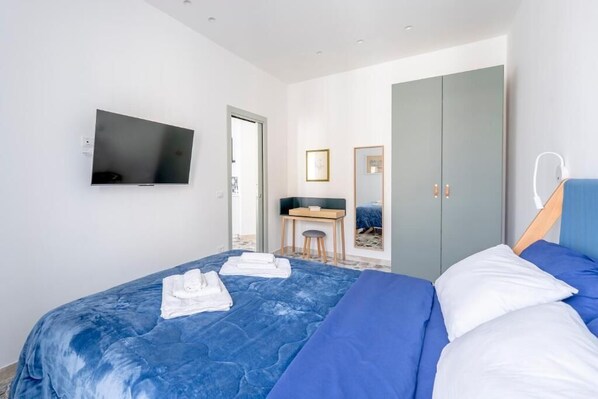 Ein modernes Hotelzimmer mit einem großen Bett, einem Schreibtisch, einem Kleiderschrank und einem Flachbildfernseher.
