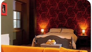 Un dormitorio con una cama, dos lámparas de noche, un ventanal y un sofá amarillo.