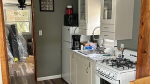 A compact kitchen with white cabinets, a gas stove, and a refrigerator. - Adorable 1-bedroom bungalow with AC in Sergeant Bluff (Sergeant Bluff)