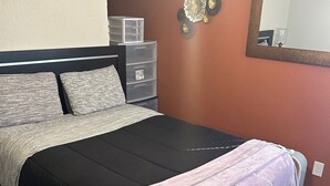 A bedroom with a bed, a dresser, and a mirror. - Adorable 1-bedroom bungalow with AC in Sergeant Bluff (Sergeant Bluff)