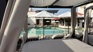 Zona junto a la piscina con sillones de descanso y sombrillas, con vista a una piscina.
