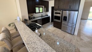 Una cocina moderna con armarios de madera oscura, electrodomésticos de acero inoxidable y encimera de granito.