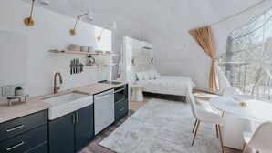Et moderne interiør i hvide farver med et køkken, spiseområde og et hyggeligt soveværelse.