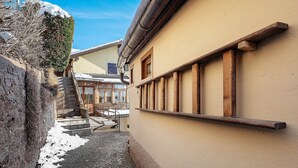 A narrow cobblestone alley with a stone wall on one side and a building with wooden beams and a window on the other. - Casa Zarina, charming two-room apartment in Cavalese (Cavalese)