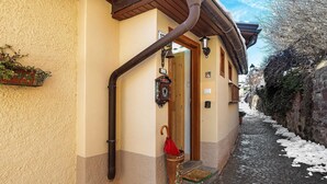 A building with a wooden door, a red umbrella, and a metal watering can on the steps. - Casa Zarina, charming two-room apartment in Cavalese (Cavalese)