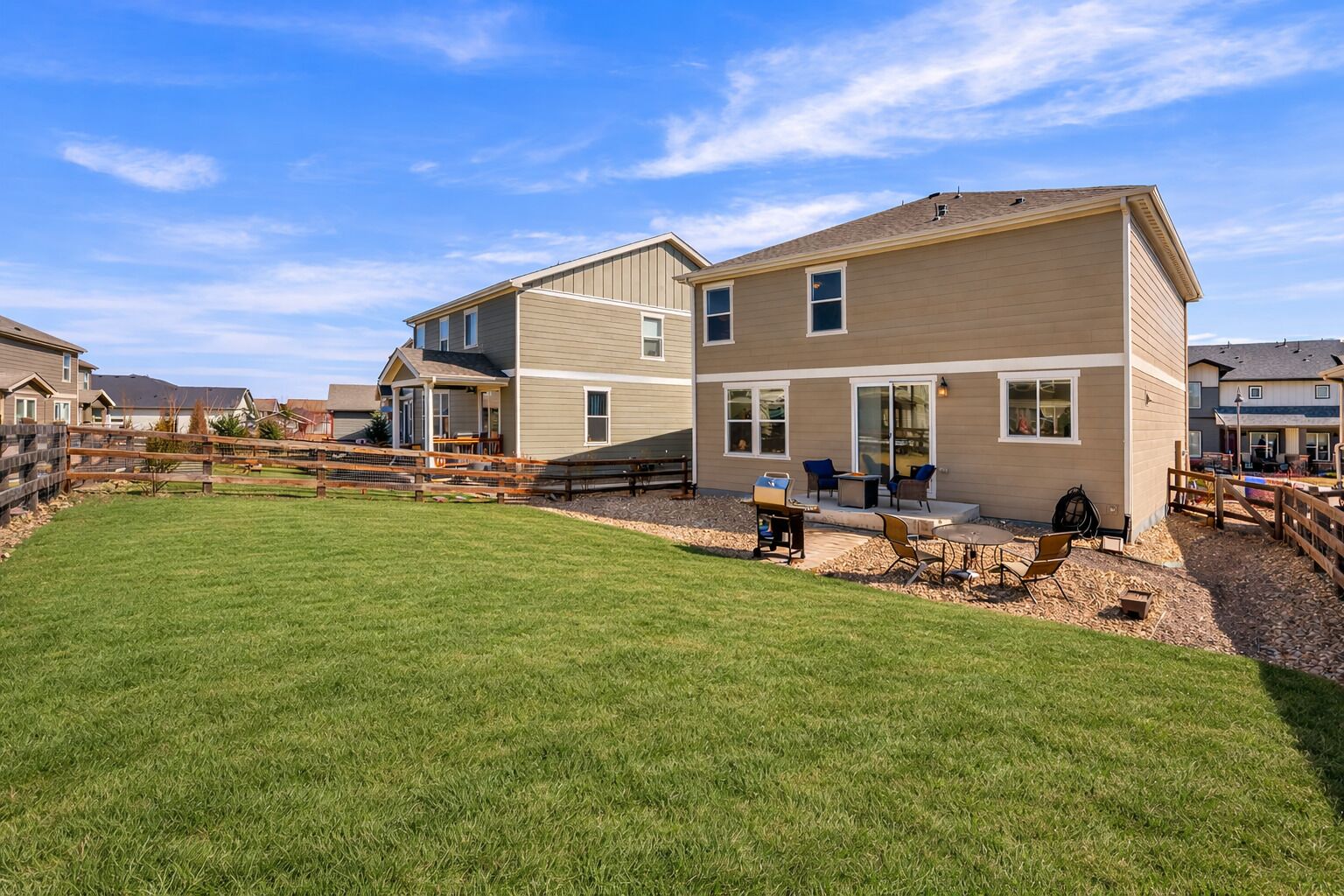 A two-story residential building with a well-maintained lawn and patio area.