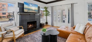 Una sala de estar moderna con chimenea, sofá de cuero y televisor montado arriba.