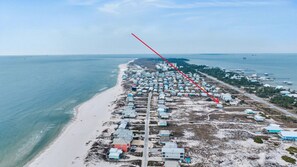 An aerial view of a coastal area with a long stretch of beach and a row of houses. - Gulf Shores Dog Friendly | Sleeps 11 + Golf Cart (Gulf Shores)