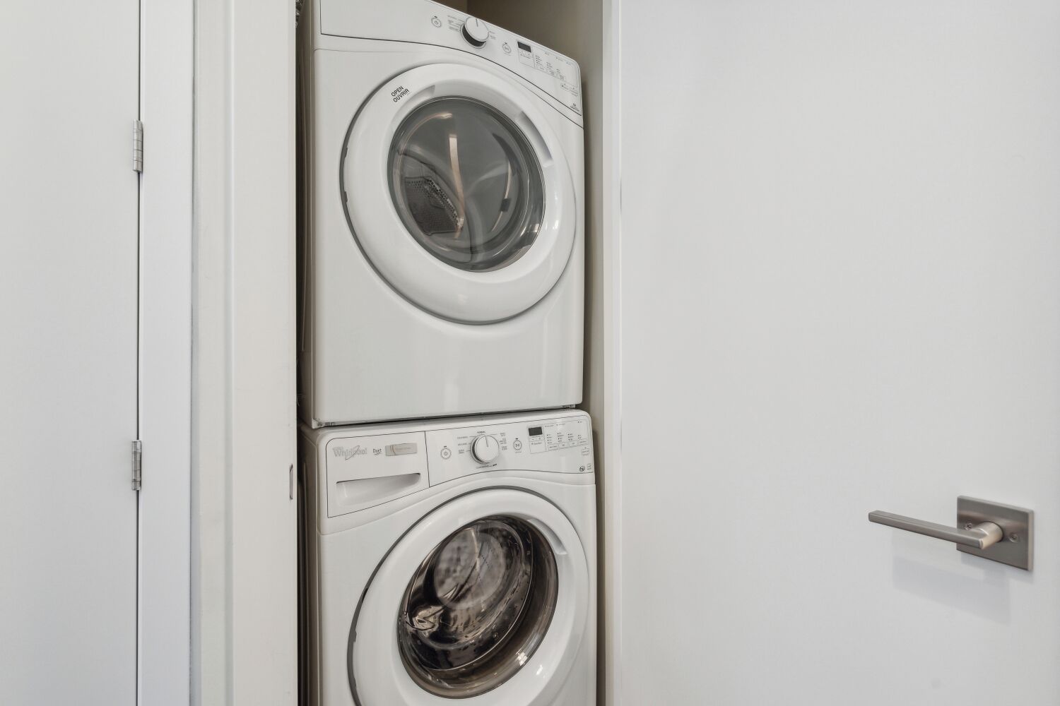 A white wall with a door and a built-in washer and dryer unit.