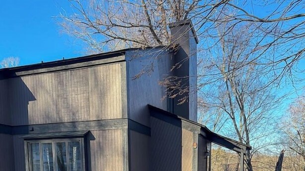 A wooden deck leading to a modern building with large windows and a chimney. - Golf, Mountain Air & Relaxation – Hideaway on the Green Awaits (Sugar Mountain)