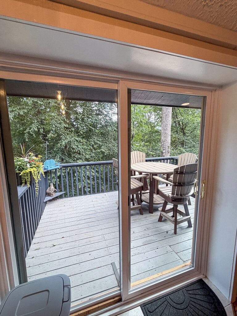 A deck with a table and chairs, a blue Adirondack chair, and a wooden fence.