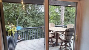A deck with a table and chairs, a blue Adirondack chair, and a wooden fence. - Golf, Mountain Air & Relaxation – Hideaway on the Green Awaits (Sugar Mountain)