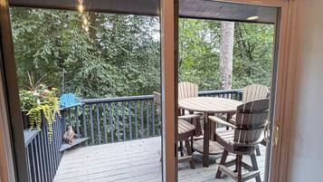 A deck with a table and chairs, a blue Adirondack chair, and a wooden fence.