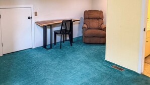 A room with a teal carpet, a wooden desk, a black chair, and a brown recliner. - Golf, Mountain Air & Relaxation – Hideaway on the Green Awaits (Sugar Mountain)