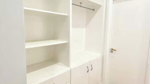 Ein weißer Kleiderschrank mit offenen Regalen und einer Tür.