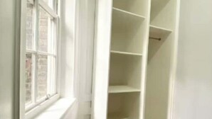 Ein helles Interieur mit Fenster und weißem Regalschrank.