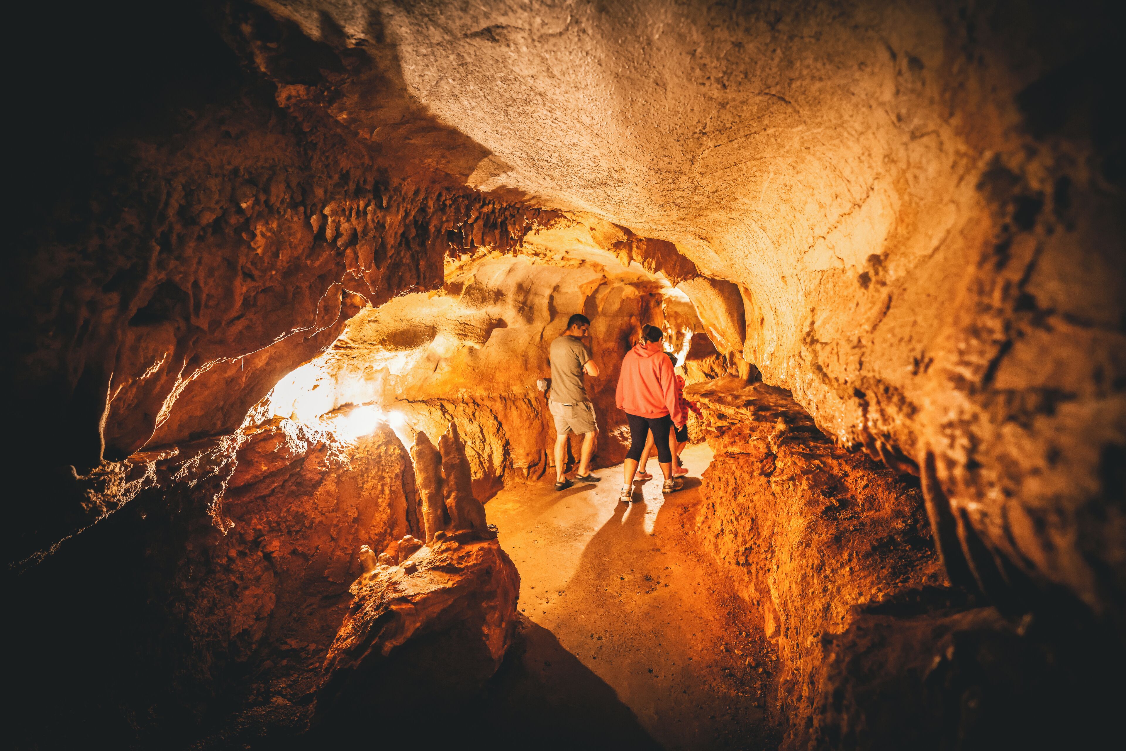 Une grotte ornée de stalactites et de stalagmites, éclairée par un système d’éclairage artificiel.
