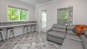 Una cocina moderna con suelo de espiga, un sofá gris y una zona de bar con taburetes.