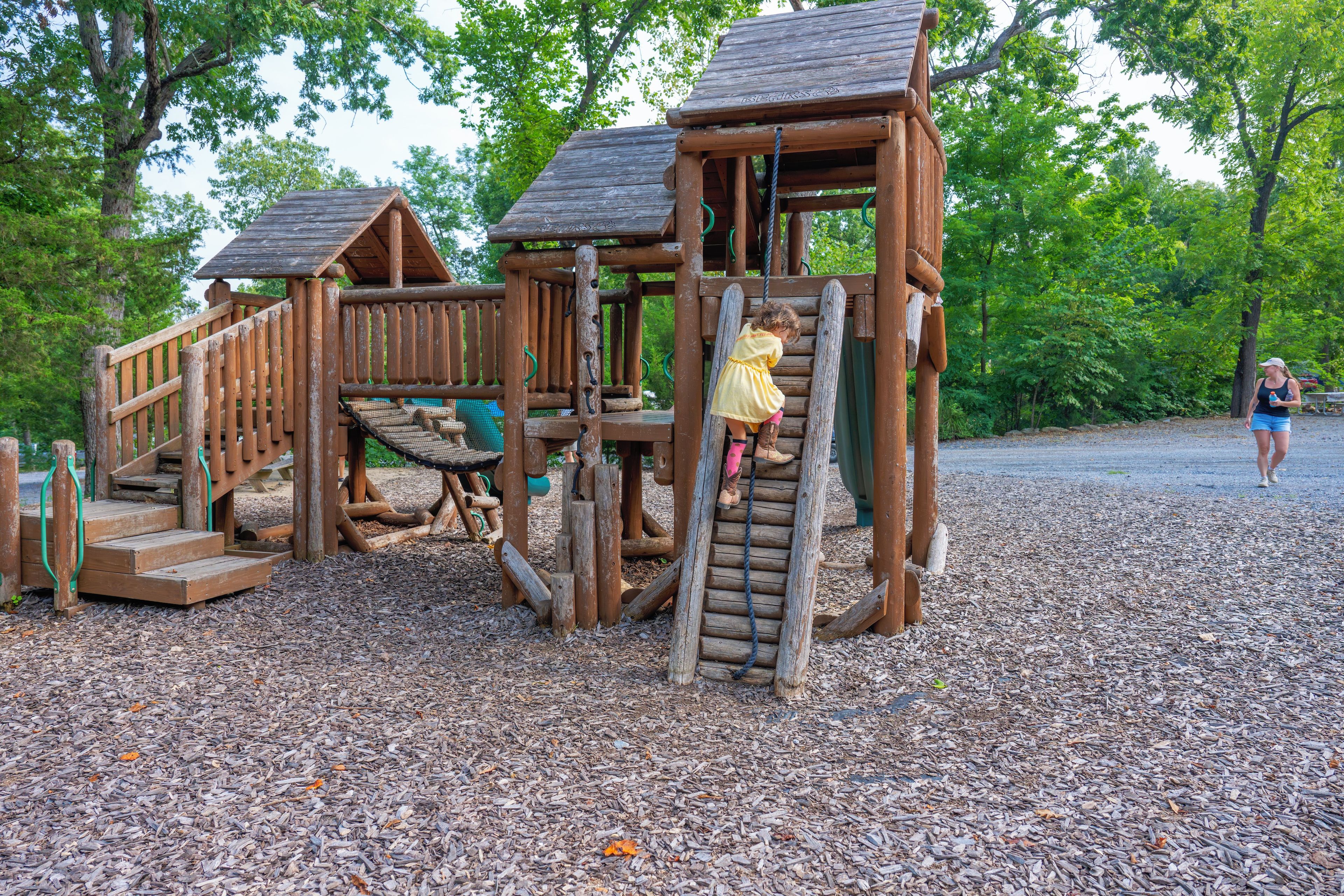 A wooden playground structure with a slide and climbing elements.